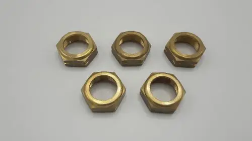 Fünf Verbindungsmuttern aus Messing, hergestellt von Remeha, in hexagonalem Design. Auf einem grauen Untergrund angeordnet.